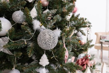 Beyaz klasik şöminenin arka planına karşı yumuşak pembe renklerde Noel süslemeleri ile süslenmiş Noel ağacı. Yeni yıl şenlikli oturma odasının ayrıntıları.