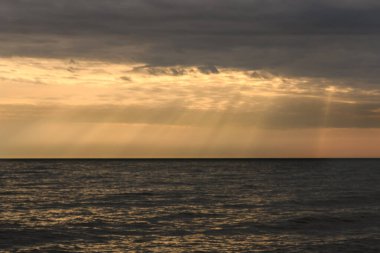 Baltık Denizi üzerinde bulutlu gün batımı. Cennetten gelen ışınlara benziyor.