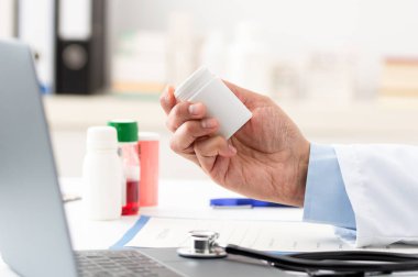 Muayene odasında reçete için form dolduran genç bir doktorun fotoğrafı.