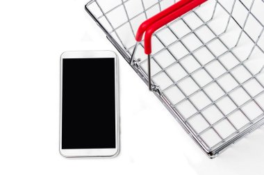 Akıllı telefon ve beyaz arka planda alışveriş sepeti metali. İnternet alışveriş kavramı