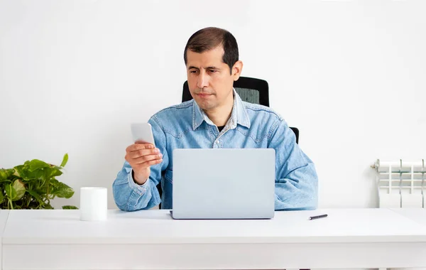 Cropped shot of a young businessman standing alone in his home office and texting on his cellphone