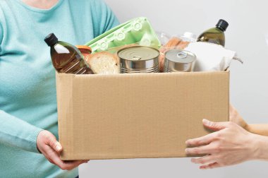 Bağış kutulu gönüllüler. Gri arka planda gıda malzemeleri var.