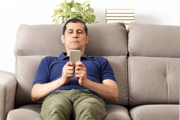 Hombre Aburrido Revisando Teléfono Móvil Sentado Sofá Sala Estar Casa — Foto de Stock