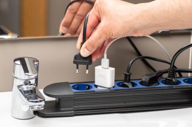 Banyodaki elektrik prizinin fişini takan bir kadının el fişini çek.