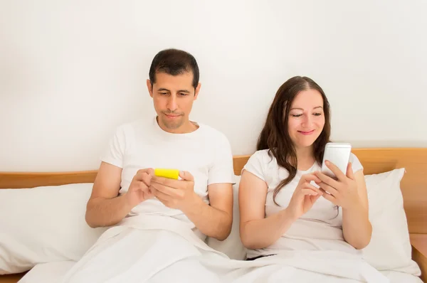 Met behulp van smartphones in het bed — Stockfoto