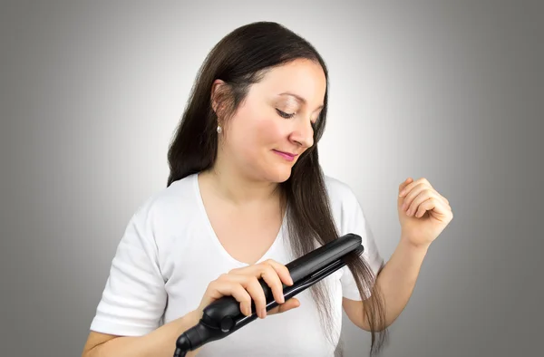 Smoothing my hair with the flat iron — Stock Photo, Image