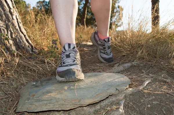 front view of closeup of feet of sportswoman walking along the path in the mountain