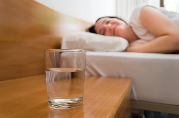 Woman sleeping with water on the night table — Stock Photo, Image