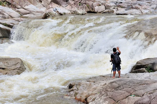 Fotógrafo tomando fotos frente a la cascada — Foto de Stock