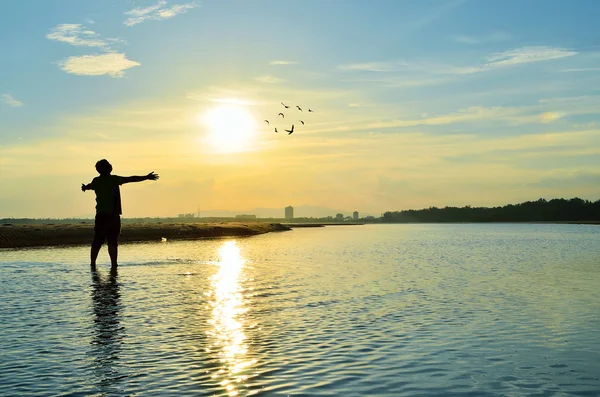 Homme levant les mains au coucher du soleil — Photo