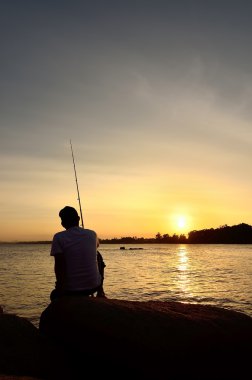 Sahilde renkli günbatımında balıkçı silueti