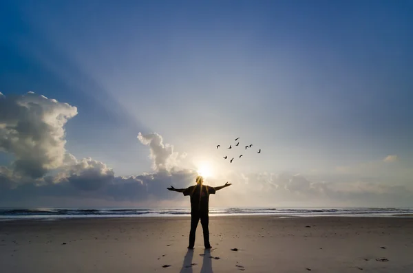 Силуэт человека, поднимающего руки или распускающего руки на восходе солнца — стоковое фото