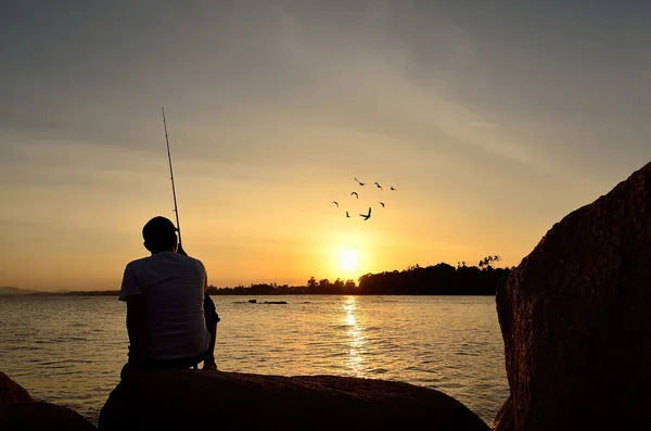 Fiskare silhuett på stranden vid färgglad solnedgång — Stockfoto