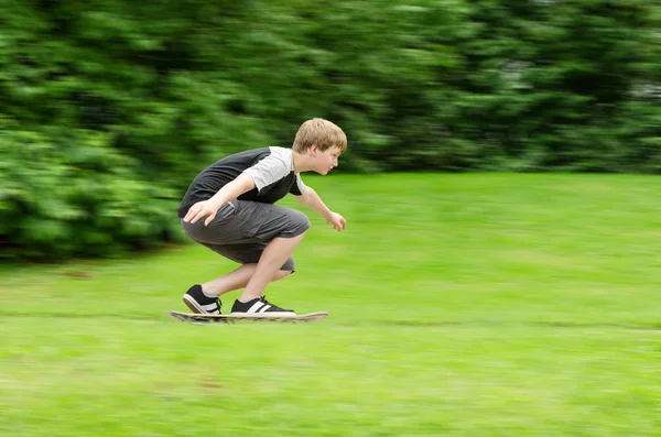 Jonge tiener kerel snel rijdt een skateboard in park Rechtenvrije Stockafbeeldingen