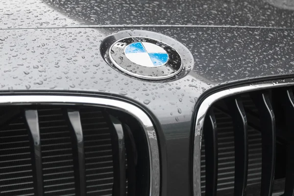 Logo de BMW en la superficie mojada de la campana del coche —  Fotos de Stock