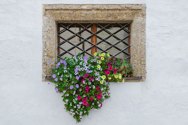 Kleurrijke bloemen op venster buitenkant van oude Europese huis — Stockfoto