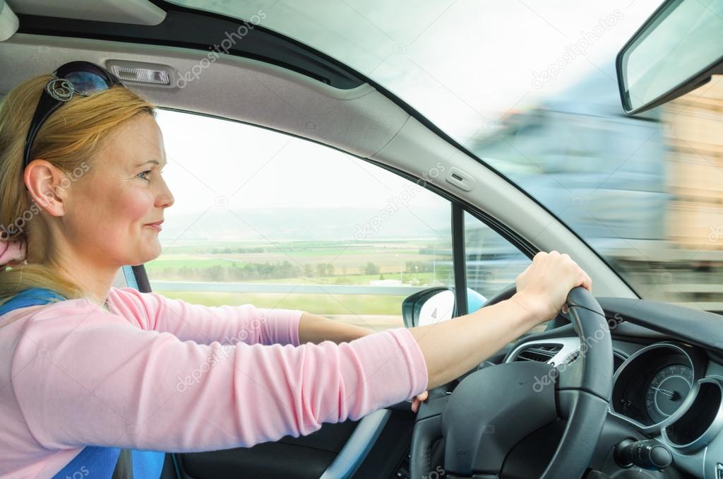 Attractive adult woman safe carefully driving car suburban road
