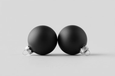 İki siyah mat Noel topu, pürüzsüz gri bir arka planda..