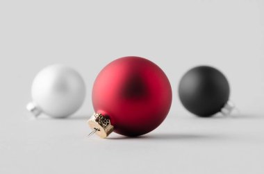 Kırmızı, beyaz ve siyah renkli Noel topları pürüzsüz gri bir arkaplanda..