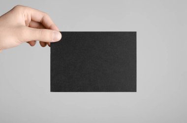 Siyah A6 Flyer / Kartpostal / Davetiye Model-up - Gri arkaplanda siyah bir el ilanı tutan erkek eller.