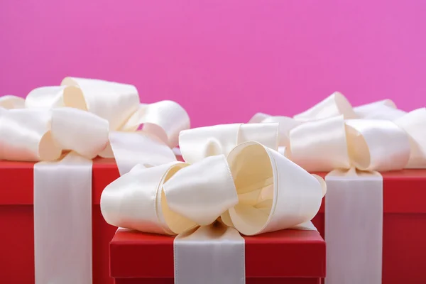 Rote und weiße Geschenke auf rosa Hintergrund. — Stockfoto