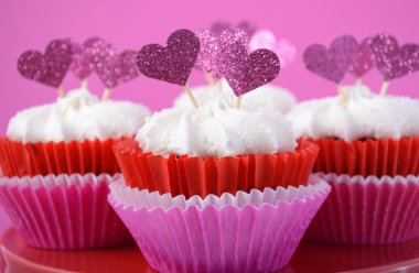 Kalp şekli toppers ile pembe ve beyaz cupcakes. 