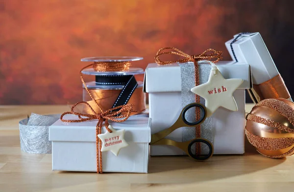 Weihnachtsgeschenke aus Kupfer und Weiß auf festlich gedecktem Tisch gestapelt. — Stockfoto