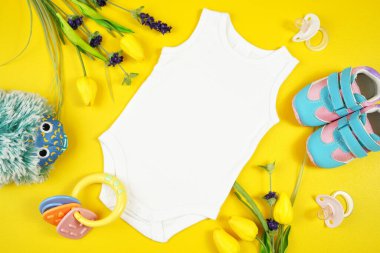 Bahar zamanı bebek kıyafetleri sarı masanın üzerinde düz bir üst görünüm. Model.