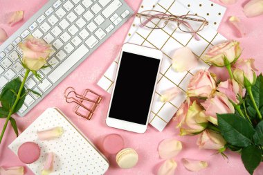 Masaüstü çalışma alanı akıllı telefon modeli, pembe arka planda pembe güller.