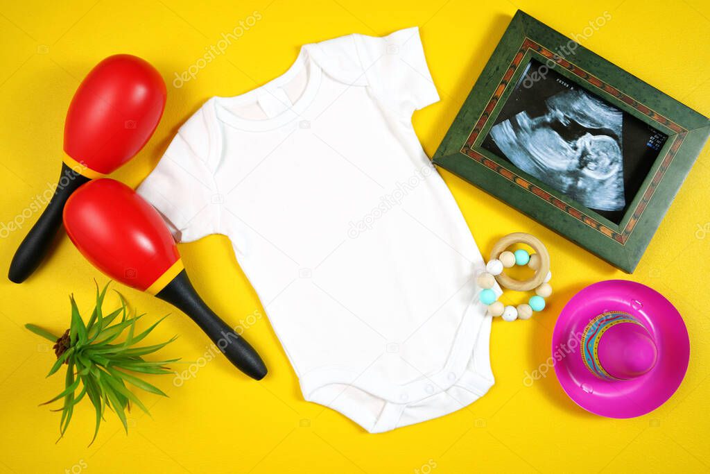 Cinco de Mayo baby romper with sonogram flatlay on a yellow table background