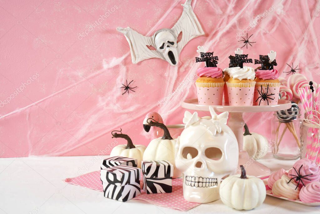 On trend pink Halloween party table with cupcakes