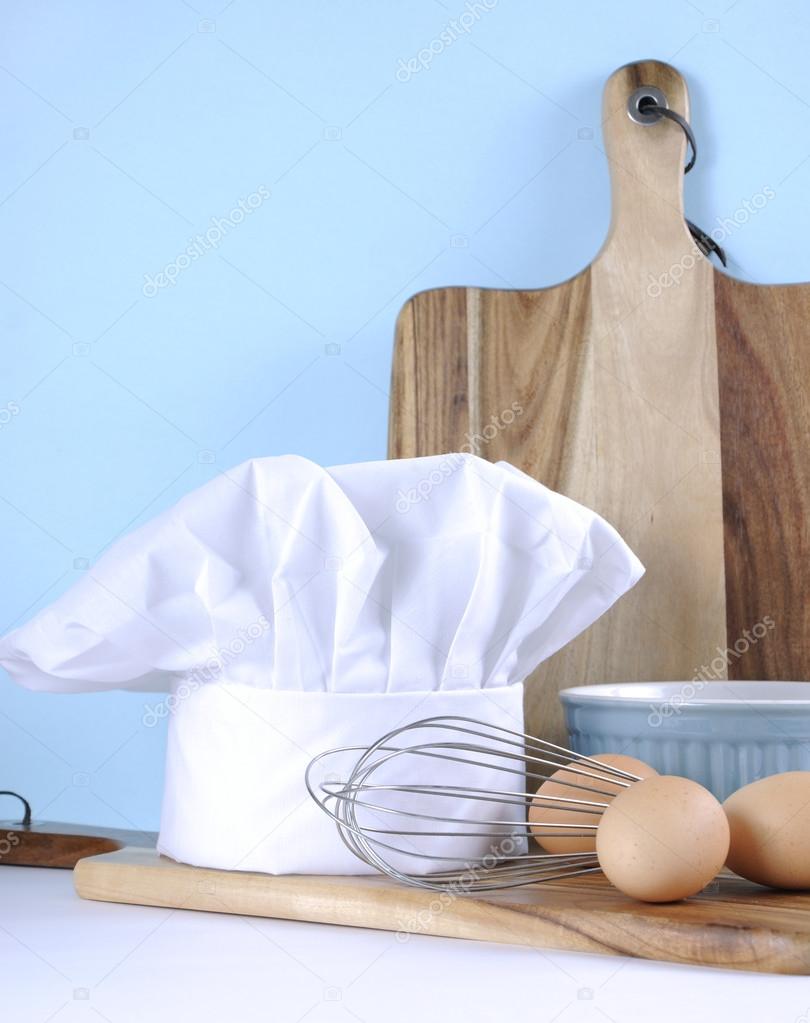 Modern blue and white kitchen with chefs hat and utensils.