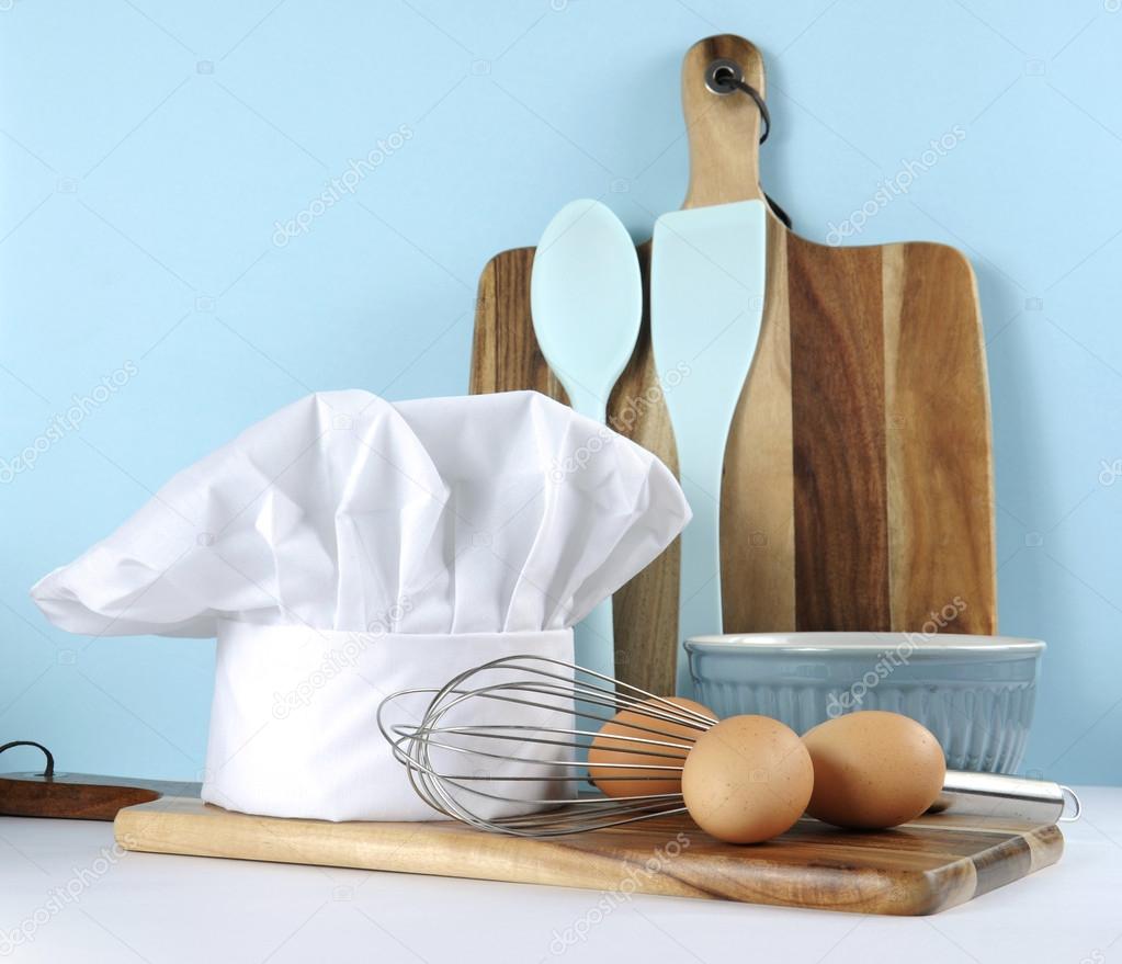Modern blue and white kitchen with chefs hat and utensils.