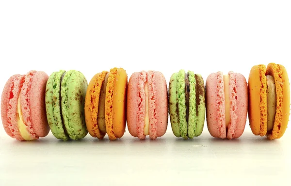 Macaroons coloridos na mesa de madeira branca . — Fotografia de Stock