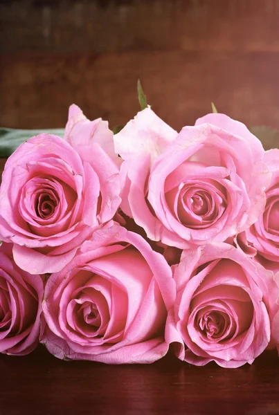 Vintage stijl roze rozen op rustieke donkere houten tafel. — Stockfoto