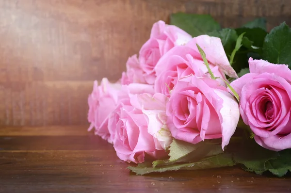 Vintage roze rozen op donkere hout achtergrond. — Stockfoto