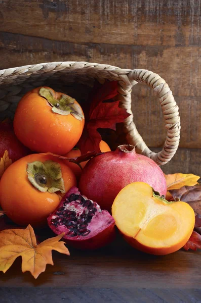Korg med färsk sharonfrukt och granatäpplen — Stockfoto