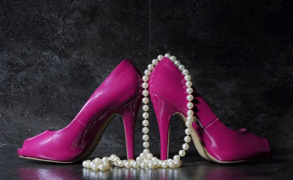 Ladies pink high heels with long strand of white pears against a Stock Image