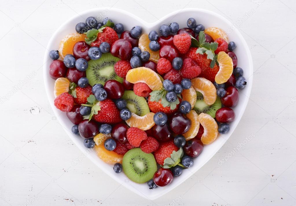 Colorful rainbow fruit in heart shape bowl.
