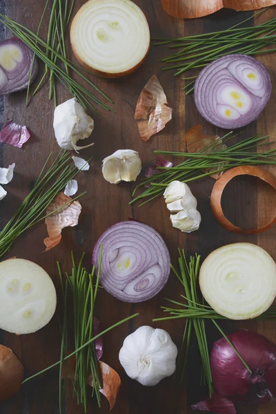 Onions, chives and garlic scattered on wood table — Stock Photo, Image