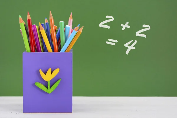 Back to school pencil box against green chalkboard. — Stockfoto