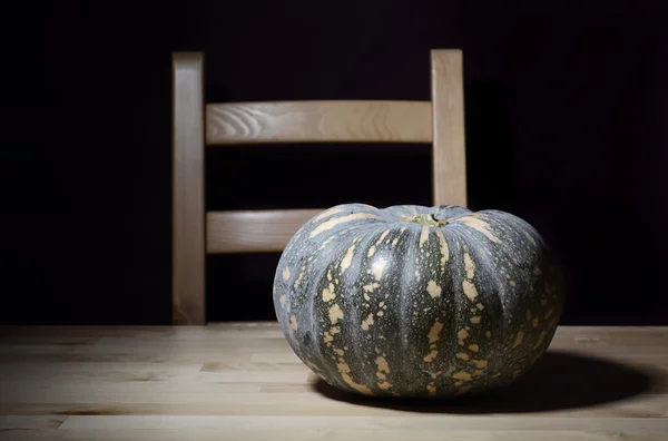 Zucca solitaria su tavolo rustico con sedia . — Foto Stock