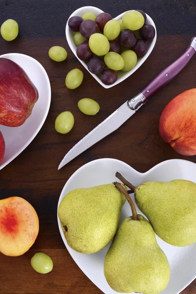 Fruta en forma de corazón placas en la mesa de madera . — Foto de Stock