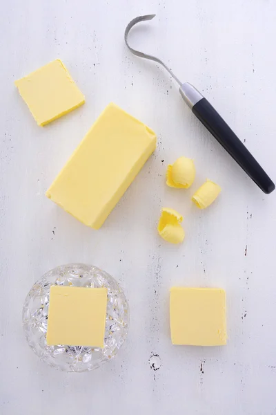 Mantequilla sobre mesa de madera blanca . — Foto de Stock