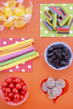 Bright colorful candy on orange wood background.