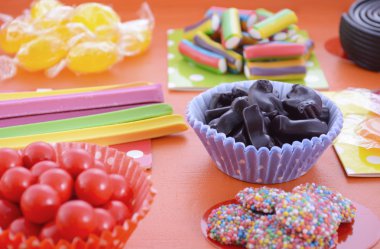 Bright colorful candy on orange wood background.