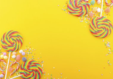 Gökkuşağı lolipop şeker parlak sarı ahşap masa üzerinde.