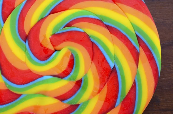 Bright rainbow lollipop candy on dark wood table. — Stock Photo, Image