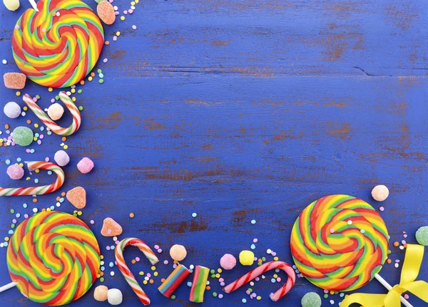 어두운 파란색 나무 테이블에 밝은 무지개 롤리팝 사탕. — 스톡 사진
