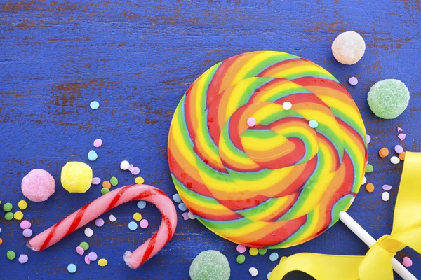 Ljusa rainbow lollipop godis på mörk blå bord av trä. — Stockfoto